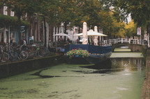 A canal in Delft with seaweed and a tourist boat