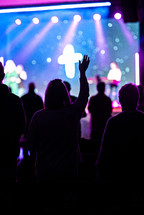 silhouettes of people at a worship service with hands raised 
