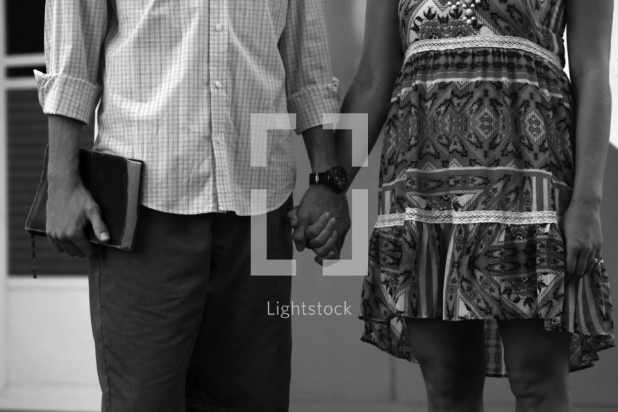 a couple holding hands and carrying a Bible 