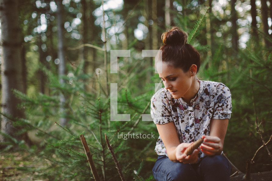 woman alone sitting in a forest thinking 