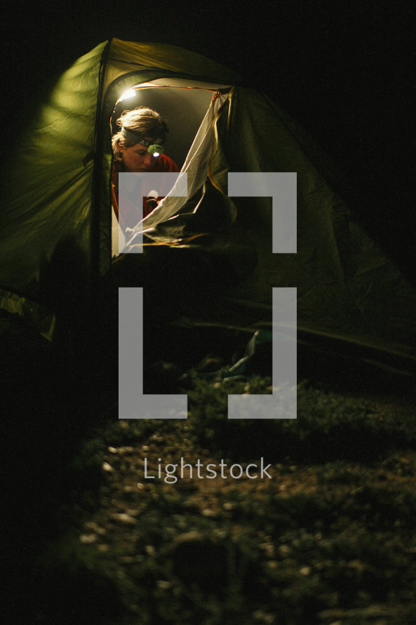 a woman in a tent with a headlamp 