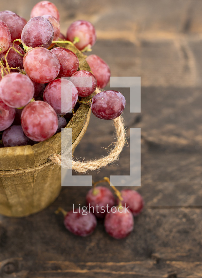 Rose grapes in wooden bucket on a woden tabl