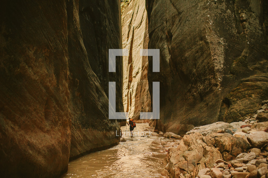 woman hiking through a river in a canyon 