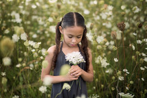 girl in a field holding wildflowers 