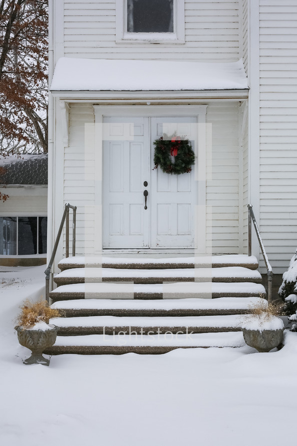 The entrance of an old country church in the snow.