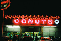 People shopping at a donut shop at night.