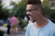 headshot of a young man laughing at an outdoors summer party 