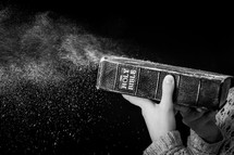 blowing dust off a Bible 