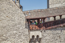 people overlooking a railing on a castles fortress walls 