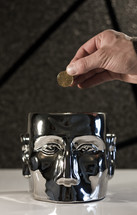 Mind on Money; hand holding coin (dollar) above a metal head.