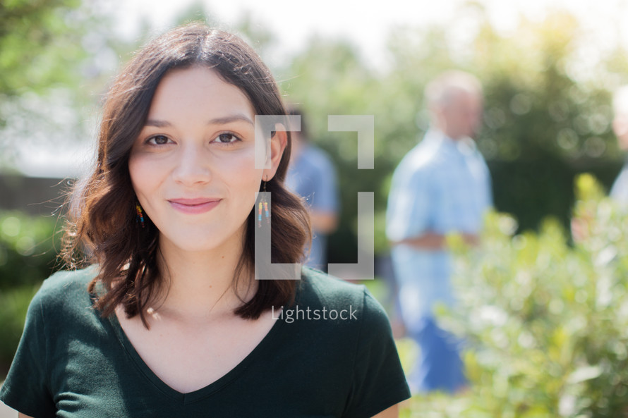 headshot of a young woman and friends talking at a backyard summer party