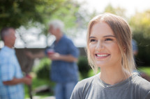 headshot of a young woman and friends talking at a backyard summer cookout 