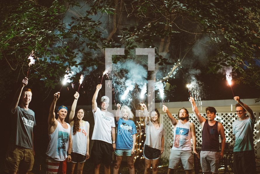 young adults holding up sparklers 