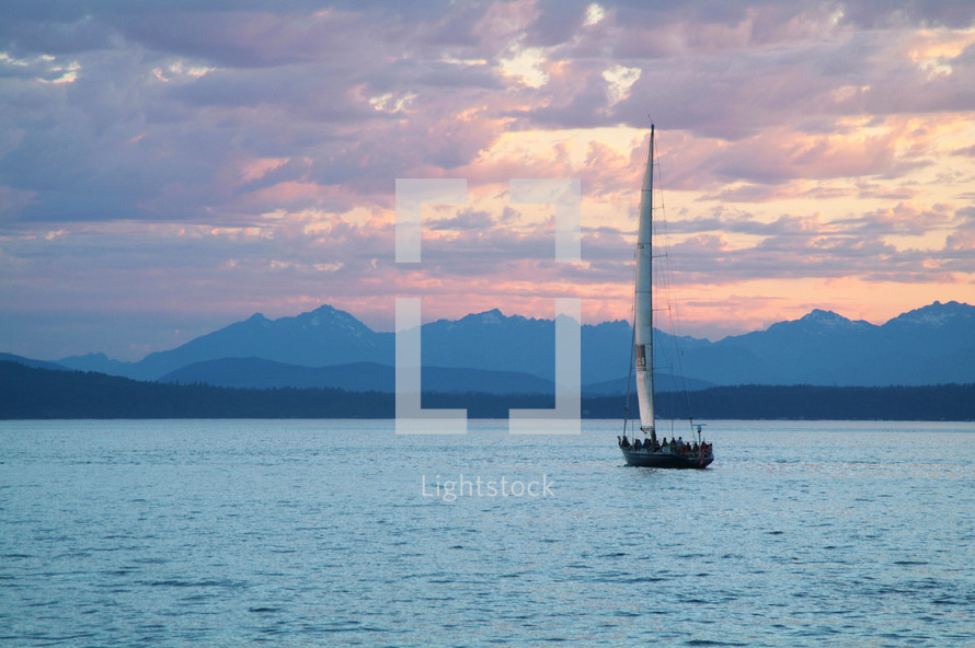 A sailboat on a lake surrounded by mountains.