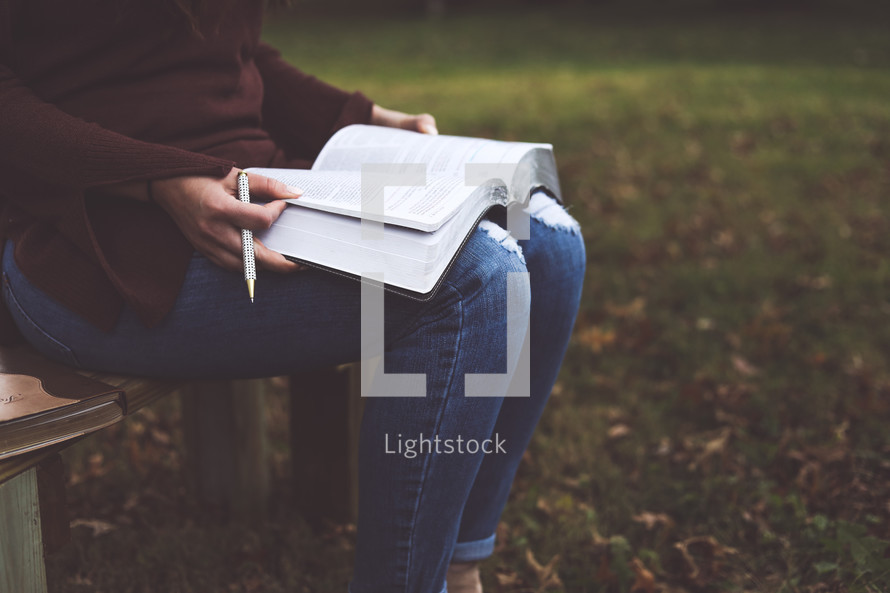 a woman reading a Bible outdoors  