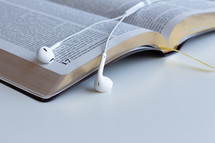 earbuds on the pages of an open Bible 