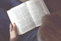 a man reading a Bible on his lap 