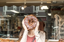 a woman holding a giant donut in front of her face 