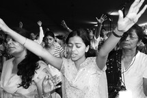 Indian woman with her hands raised in worship to God