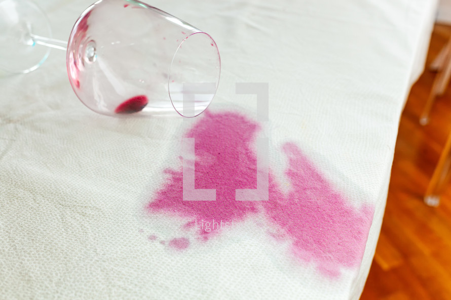 Spilled wineglass with a red spot on tablecloth
