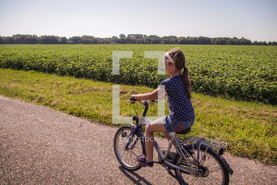 a girl child riding a bike on a rural road in The Netherlands 
