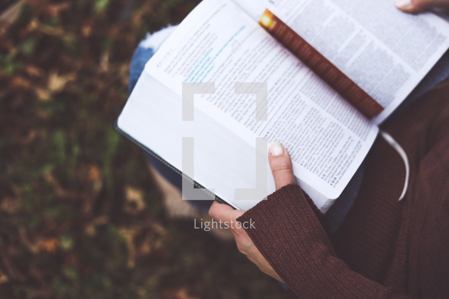 a woman reading a Bible outdoors 