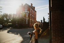 woman walking on a sidewalk downtown and a brick house 