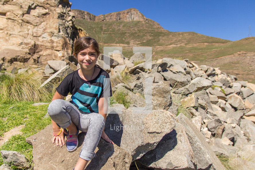 a girl sitting on a rock 