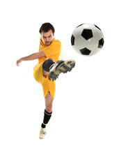 Young man in a yellow soccer uniform kicking a soccer ball