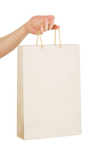 Hand holding a white paper bag with handles.