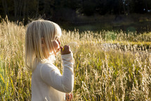 girl child blowing bubbles in a field 