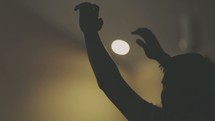 Silhouette of a man with arms raised in a lighted room.
