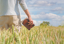 man holding a Bible in a wheat field 