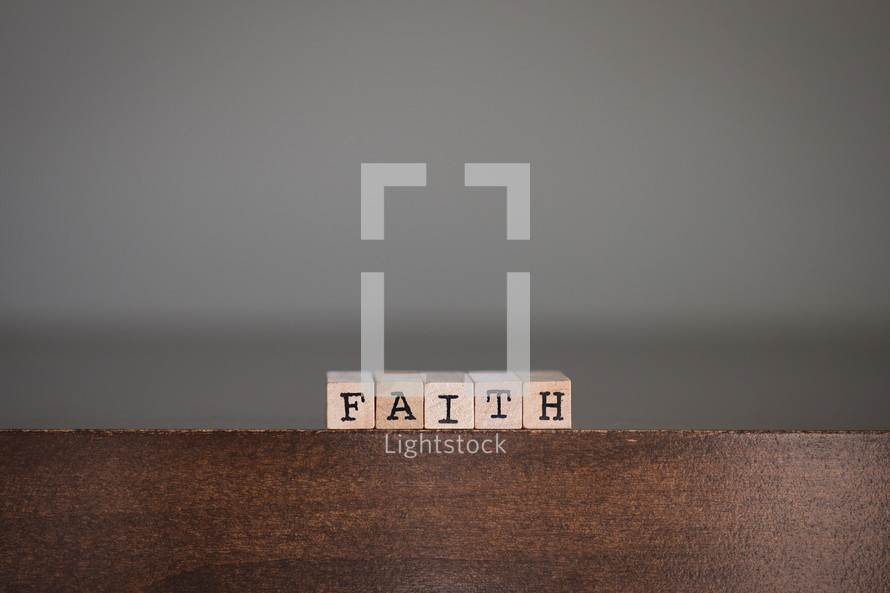 Wooden tiles spelling "Faith" on wooden table