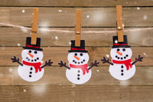snowman cutouts hanging by clothespins 
