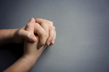 praying hands against a gray background 