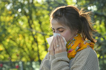 a woman blowing her nose into a tissue 