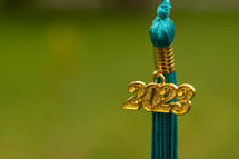 a gold and teal tassel with a green background