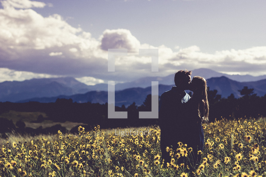 couple kissing in a field of wildflowers 