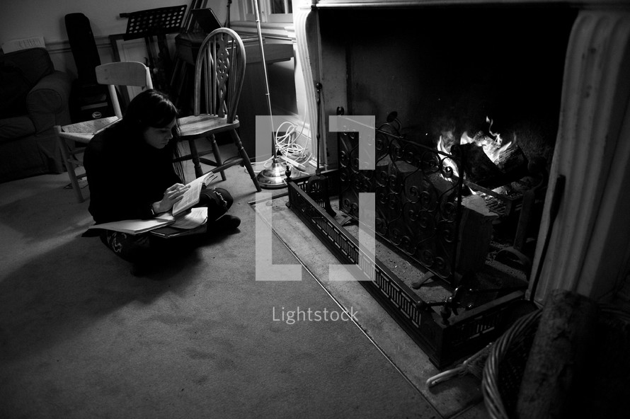 woman reading a Bible by a fireplace 