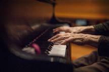 elderly woman's hands on the keys of a piano 