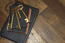Large bunch of keys on a Bible, laid on a wooden desk