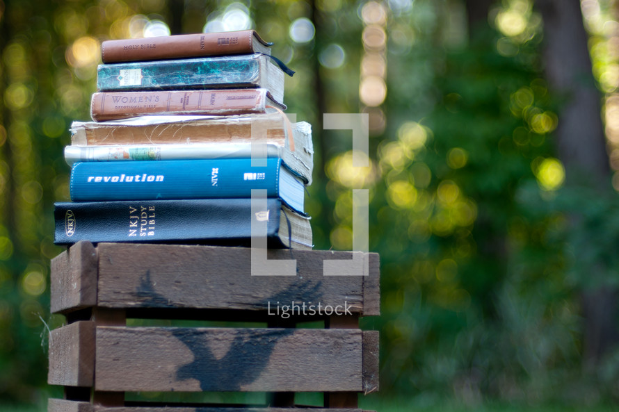 Stack of Bibles on a wooden crate outside.