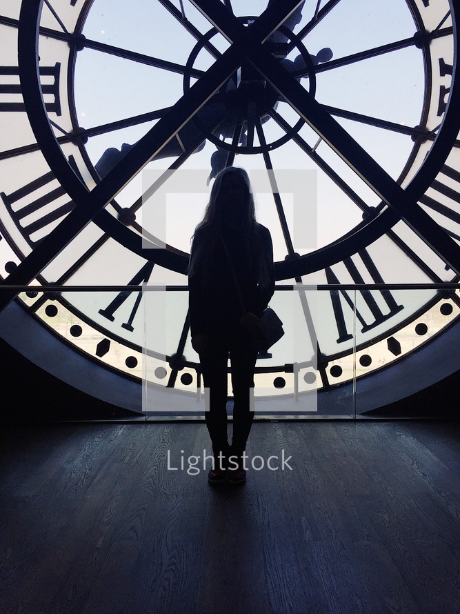 a woman standing in front of a clock in a clock tower 