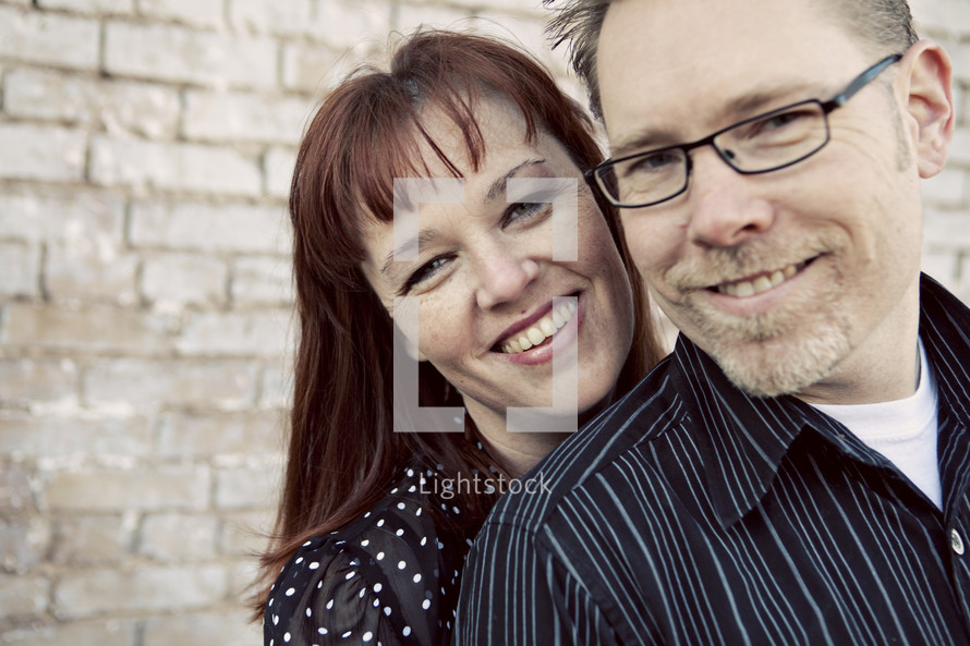 Couple in front of brick wall smiling