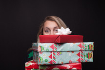 a woman holding a stack of Christmas gifts 