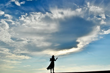 a silhouette of a woman standing with raised arms 