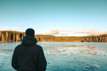 a man standing by a frozen lake 