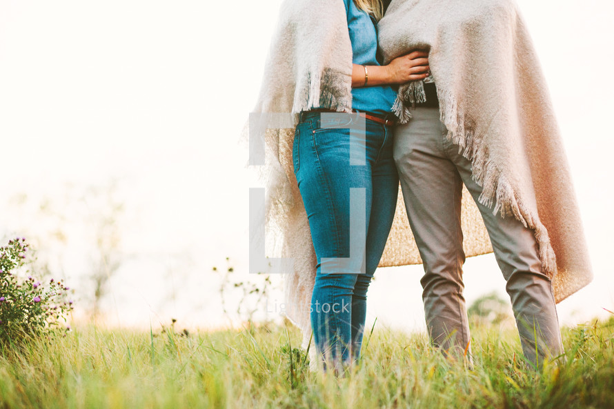 legs of a couple standing together under a blanket 