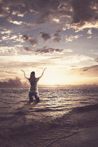 woman standing in the ocean with her hands raised in worship to God